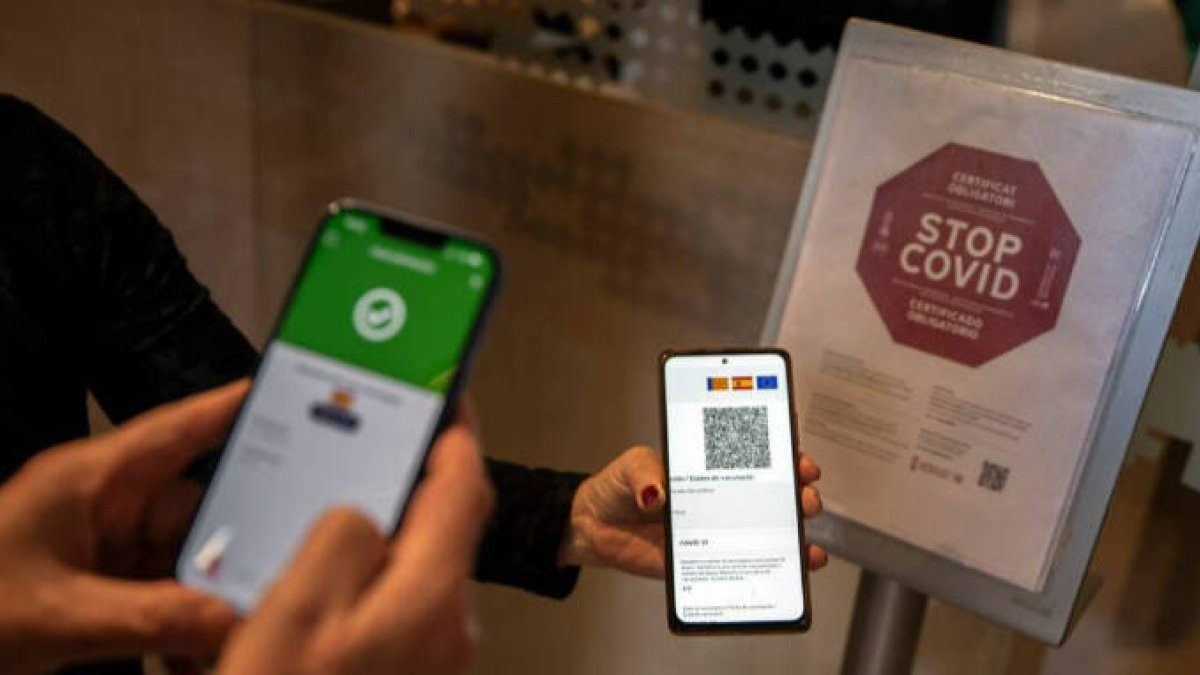 Una persona muestra el certificado covid en la entrada de un restaurante