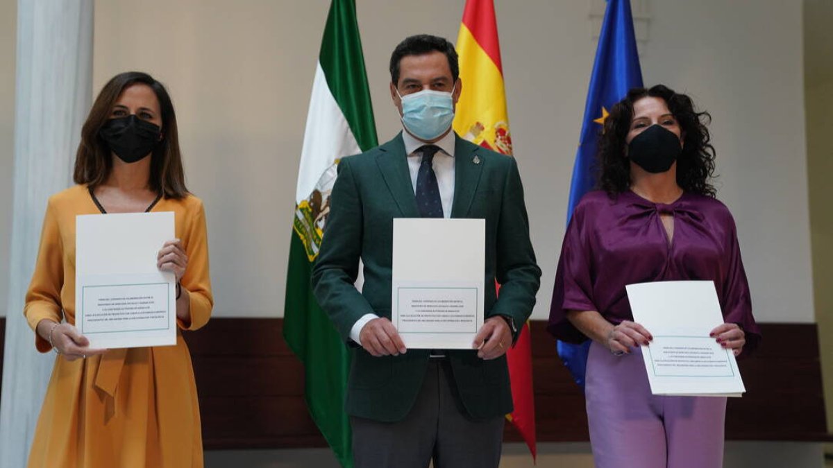 La ministra de Derechos Sociales, Ione Belarra; el presidente de la Junta de Andalucía, Juanma Moreno; y la consejera de Políticas Sociales, Rocío Ruiz, hoy durante la firma del acuerdo en Sevilla.