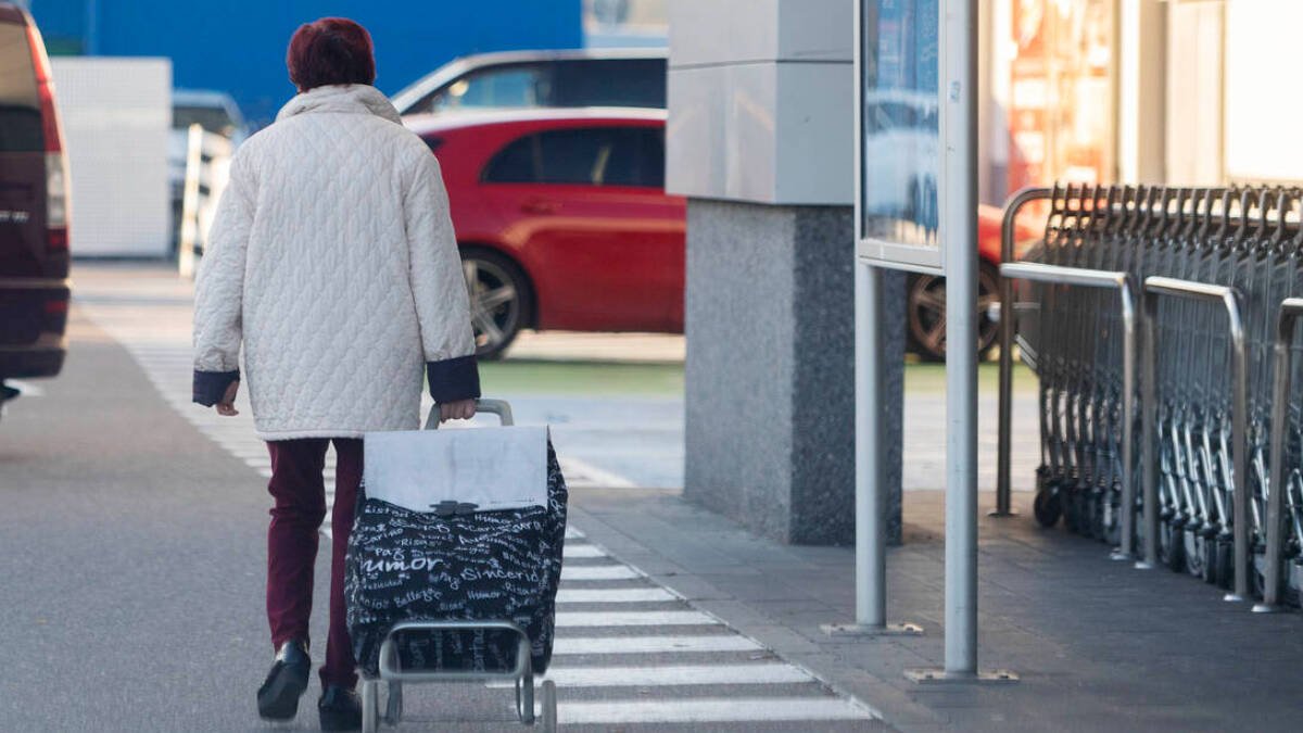 Una mujer sale de un supermercado con un carro de la compra.
