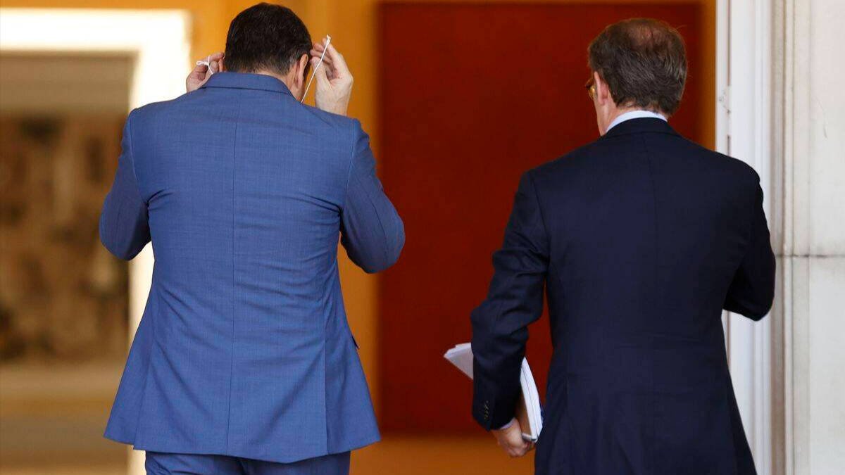 Sánchez y Feijóo, de espaldas, accediendo a La Moncloa.