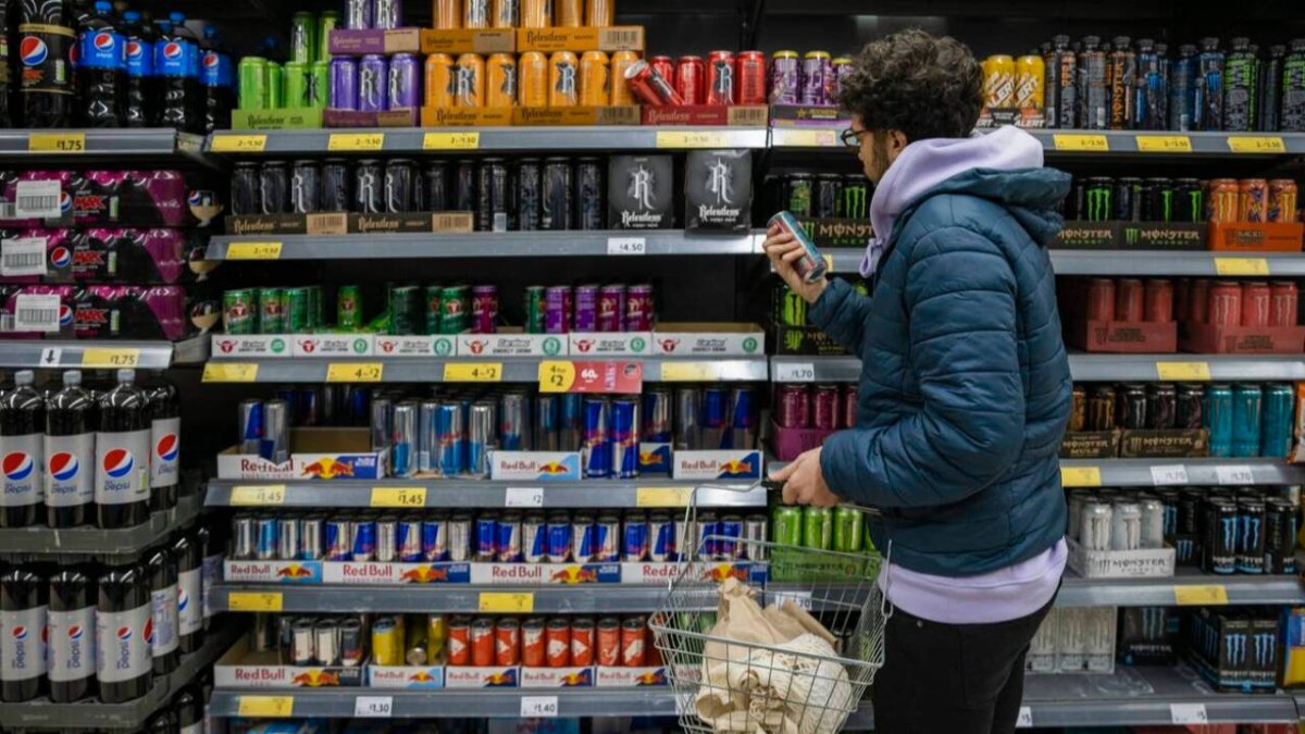 Imagen de un joven comprando bebidas energéticas en un supermercado