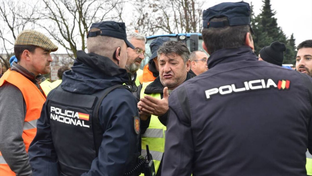 Un grupo de agricultores manifestándose frente a unos Policías