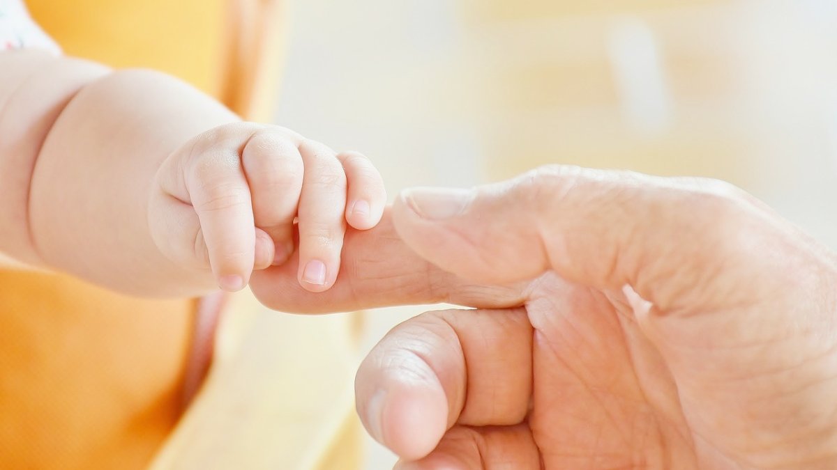 Imagen de una mano de un bebé y su madre.