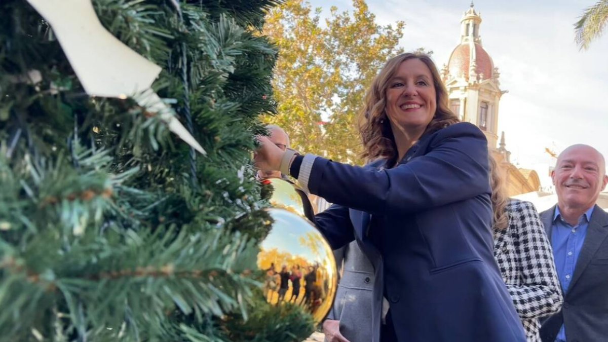 María José Catalá coloca la decoración en el árbol de la plaza del Ayuntamiento