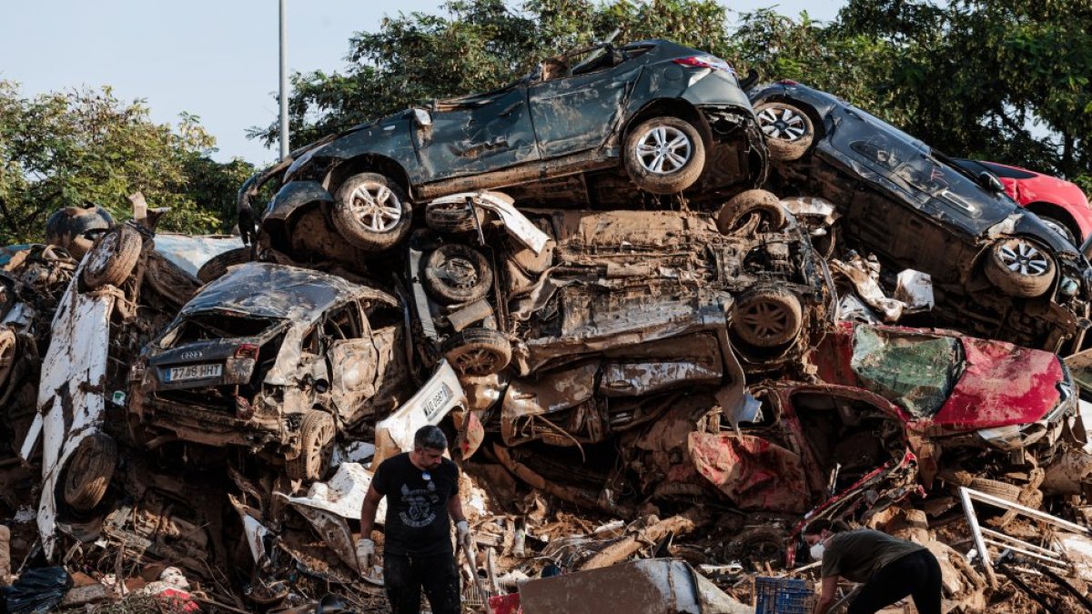 Varias personas limpian entre coches amontonados en Alfafar