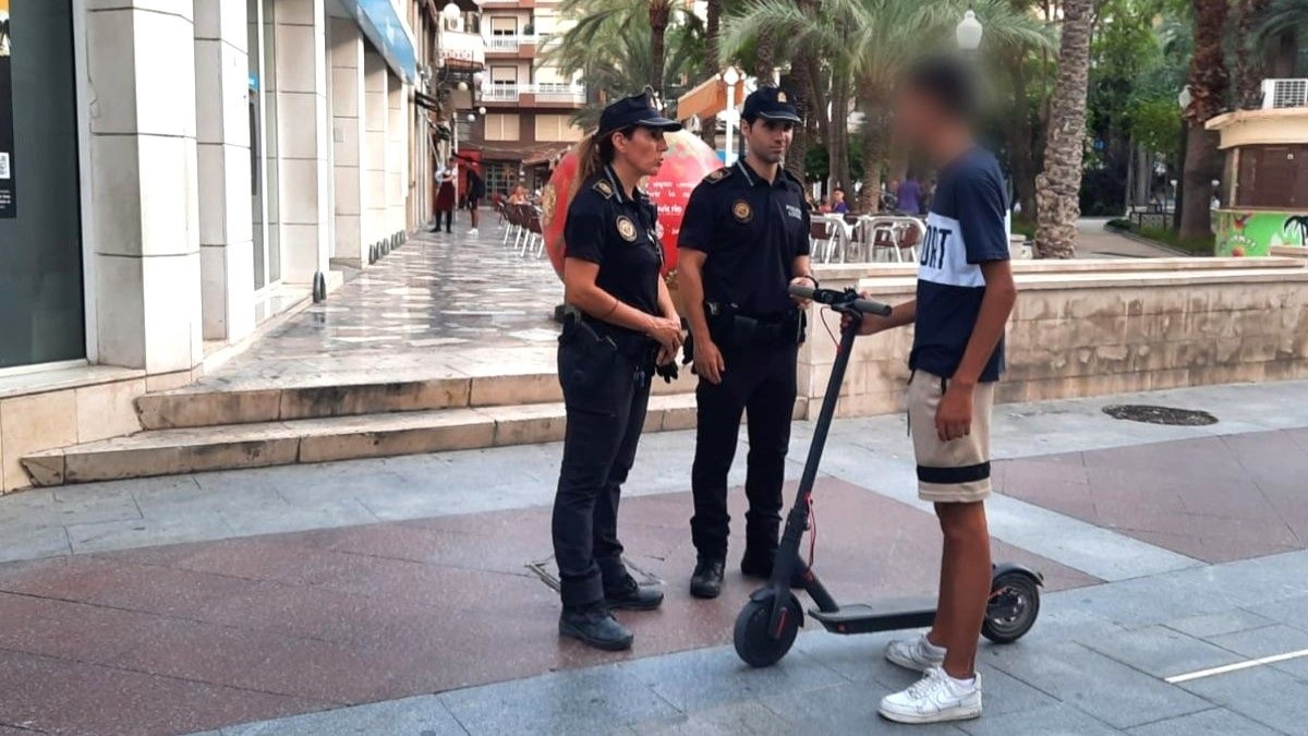 Agentes de la Policía Local de Elche (Alicante), junto a un joven que circula en un patinete eléctrico