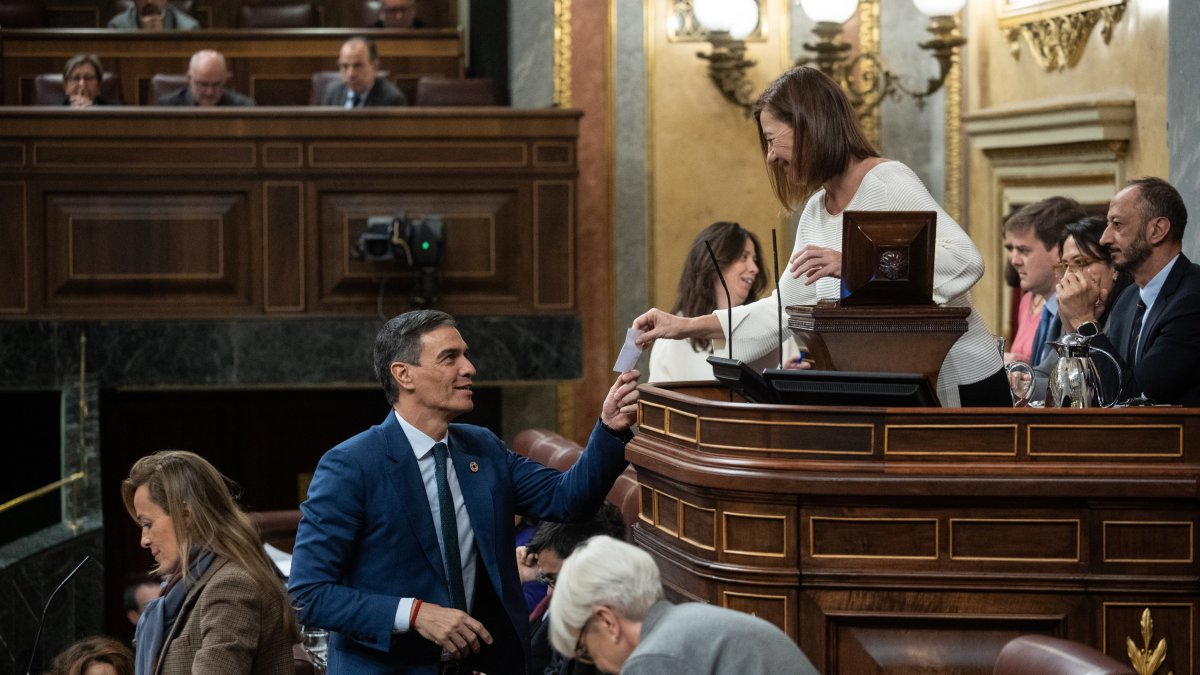 El presidente del Gobierno, Pedro Sánchez, entrega su voto a la presidenta del Congreso, Francina Armengol, en el Congreso.