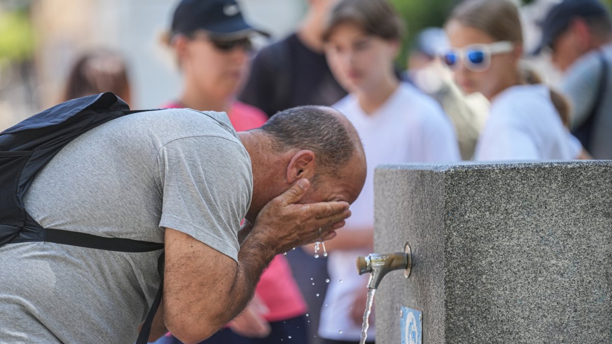 Un hombre se refresca en fuente pública.