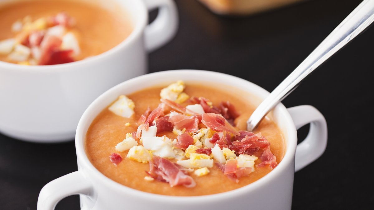El salmorejo tradicional mantiene su textura espesa y cremosa gracias al pan, acompañado de jamón y huevo duro.