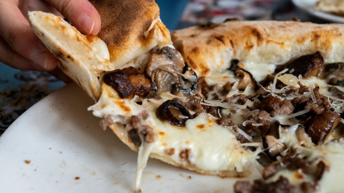 La pizza trufada lista para servir combina queso fundido, champiñones y un toque de carne sobre una base crujiente.