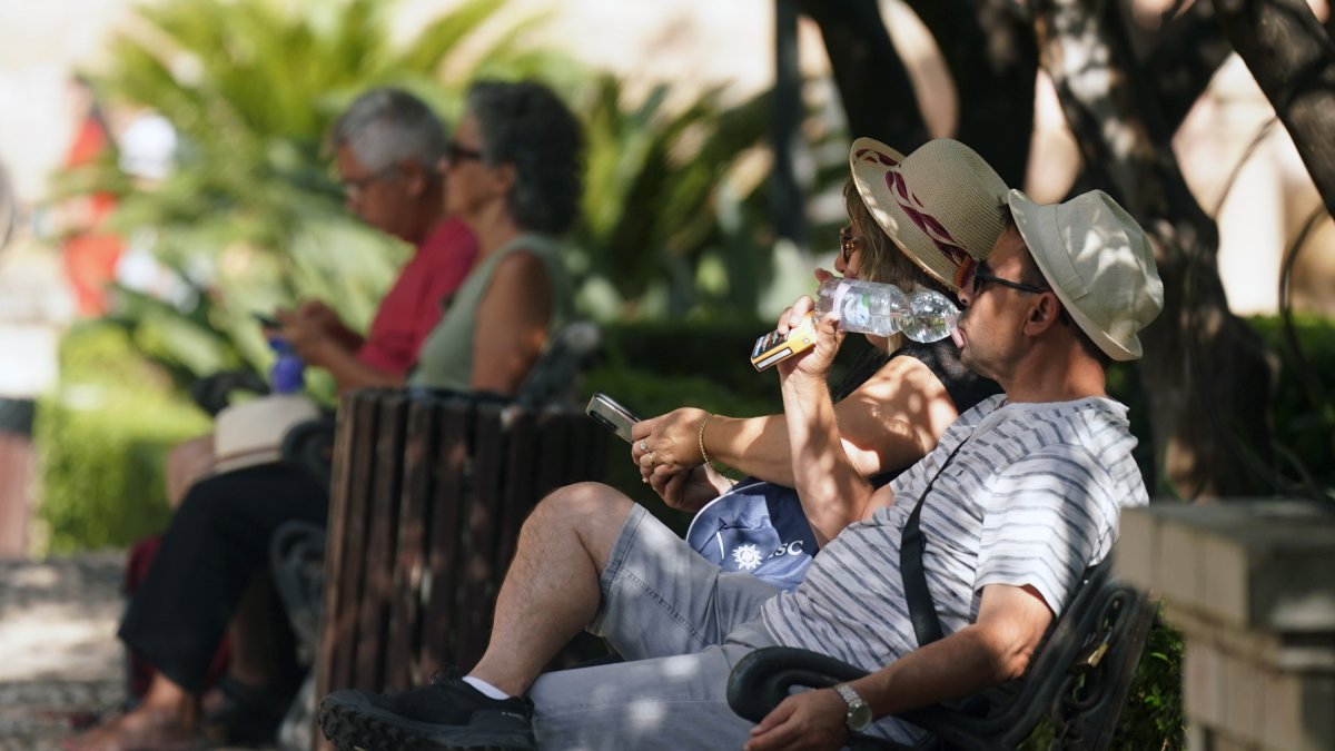 Dos personas con ropa veraniega y sombreros en Málaga.