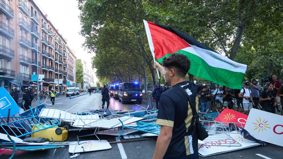 Un joven con una bandera de Palestina en Atocha, el día de la etapa 21 de la Vuelta Ciclista a España.