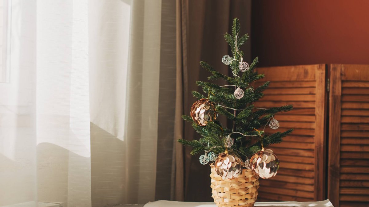 Un mini abeto natural decorado con elegancia sencilla: bolas doradas, luz suave y una cesta trenzada que eleva cualquier rincón navideño sin esfuerzo.