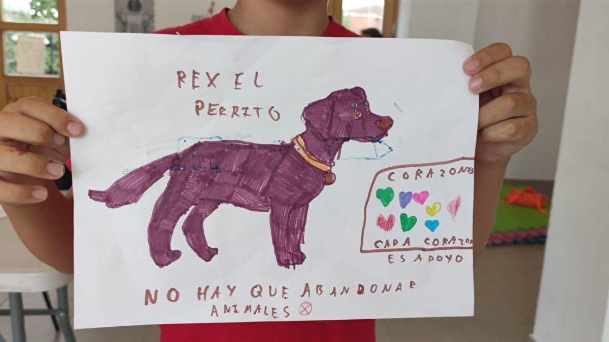Niña sostiene el dibujo de un perro