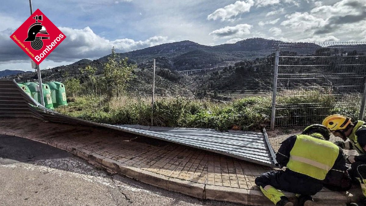 Efectivos de los bomberos, retirando una valla caída sobre una carretera.