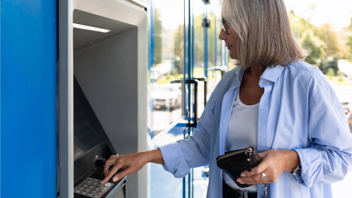 Una mujer utiliza un cajero automático para retirar dinero en efectivo, una práctica habitual que sigue generando dudas legales sobre los límites del efectivo en España.