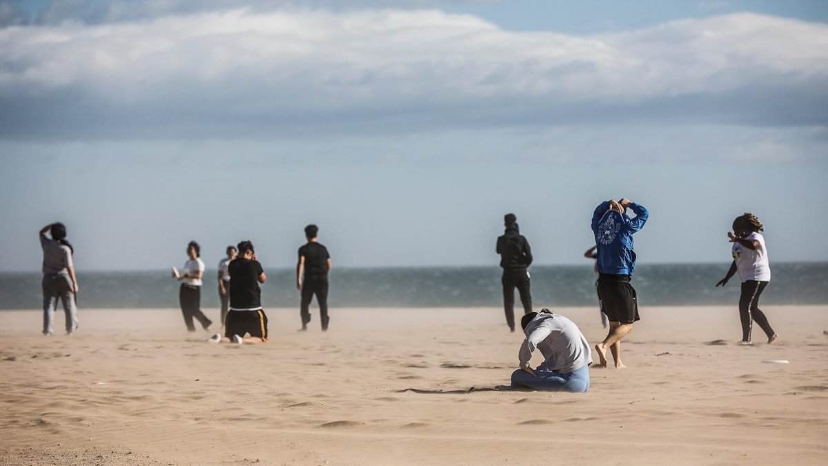 Varias personas en la playa de la Malvarrosa con fuertes rachas de viento