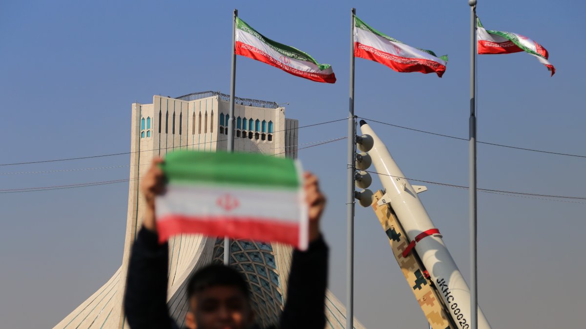 Un niño iraní sostiene una bandera de su país cerca de los misiles de fabricación iraní en la plaza Azadi (libertad) de Teherán.