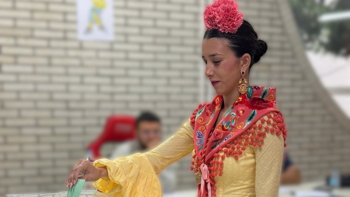 Una joven vestida de flamenca acude a votar este 17M en Andalucía.