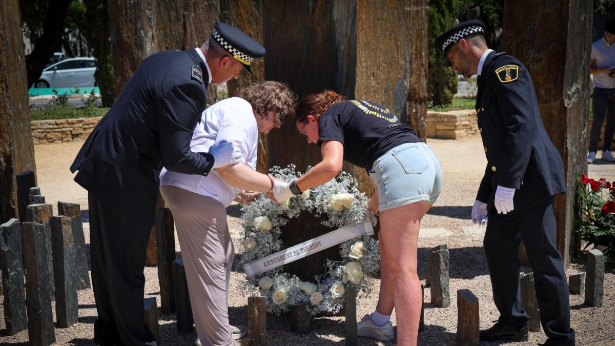 Momento en que dos agentes de la Policía Local de Torrent y dos familiares de las víctimas depositan la corona de flores en el monumento.