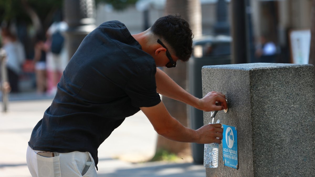 Una persona se refresca en una fuente.