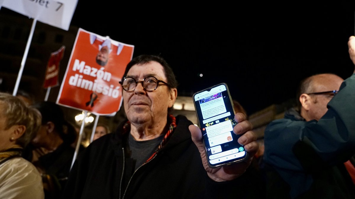 Un hombre muestra la alerta en su móvil durante una manifestación en contra de Mazón