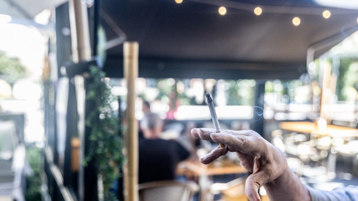Una persona fumando en la terraza de un bar.