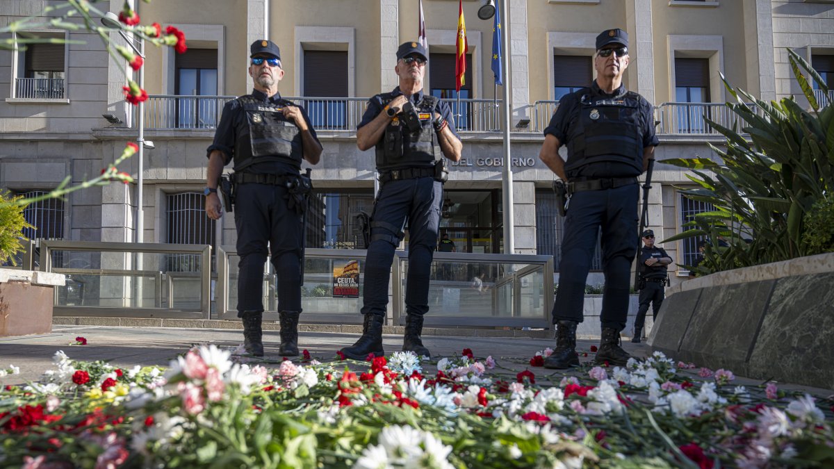 Policías ante claveles lanzados por numerosas personas durante una manifestación frente a la Delegación del Gobierno de Ceuta