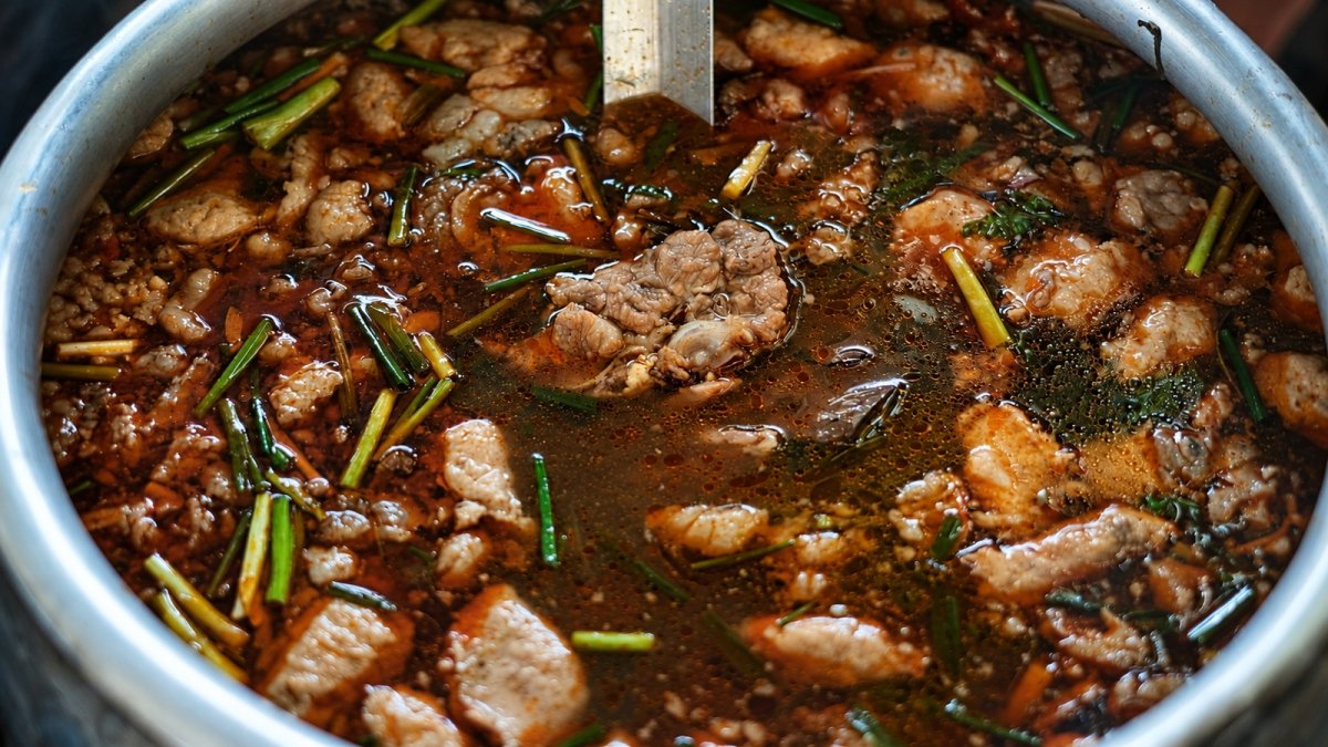 Caldo con carne y hierbas en una olla. Imagen de recurso.