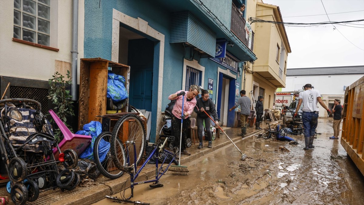 Varias personas quitan el barro de las calles mientras se acumula el mobiliario que han tenido que sacar debido a las inundaciones por las fuertes lluvias en Els Poblets