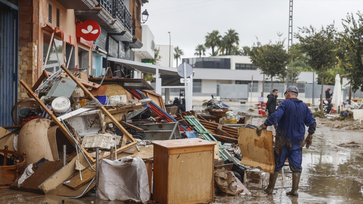 Varias personas quitan el barro de las calles mientras se acumula el mobiliario que han tenido que sacar debido a las inundaciones por las fuertes lluvias, a 19 de octubre de 2026, en Els Poblets, Comunidad Valenciana