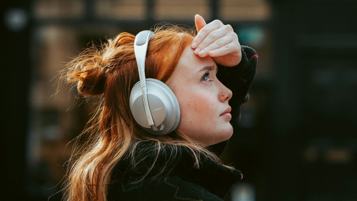 Una mujer utiliza auriculares de diadema. Imagen de recurso