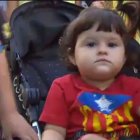 Una niña en su silla de paseo ataviada con una camiseta con la estelada impresa.