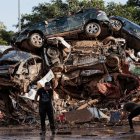 Varias personas limpian entre coches amontonados en Alfafar