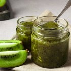 Mermelada casera de kiwi con semillas de chía en tarros de cristal, acompañada de rodajas de kiwi fresco.