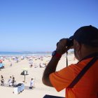 Un vigilante de la playa observa a los bañista desde su torre en Cádiz.