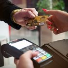 Un cliente con un reloj de oro pagando con una visa gold.