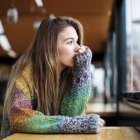Una mujer reflexiona frente a una ventana