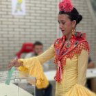 Una joven vestida de flamenca acude a votar este 17M en Andalucía.