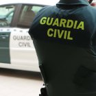 Un agente de la Guardia Civil, de espaldas, junto a un vehículo oficial.