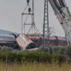 Dos grúas trabajan para retirar los vagones de los trenes accidentados