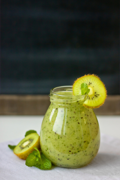 Mermelada cremosa de kiwi y chía servida en un frasco con rodajas de kiwi amarillo y hojas de menta.