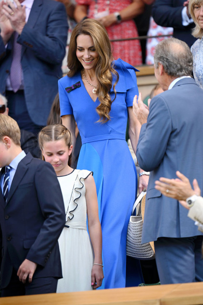 La princesa de Gales desciende las gradas del Centre Court acompañada por la princesa Charlotte, luciendo un sofisticado vestido azul con lazo estructural al hombro y joyas con historia.