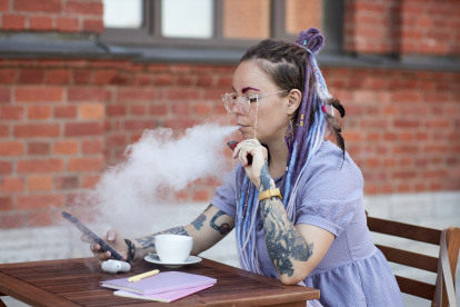 Joven vapeando en una terraza