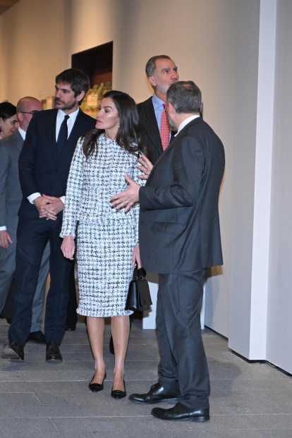 Letizia, vestida con un conjunto de tweed blanco y negro, escucha atentamente las explicaciones del comisariado de la muestra junto al rey Felipe VI.