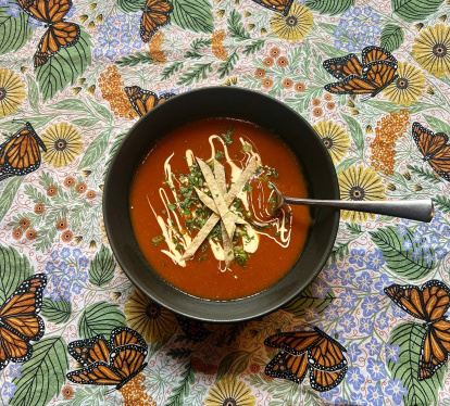 Sopa de tortilla servida al estilo tradicional: una explosión de color y sabor sobre una mesa con guiños a la cultura mexicana.